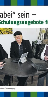 Seniorinnen und Senioren sitzen um einen Tisch und beschäftigen sich mit Smartphones und Laptops