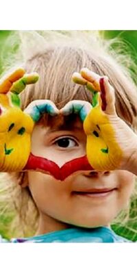 Bild zum Familienaktionstag: Ein Kind hält seine farbig bemalten Hände vor ein Auge